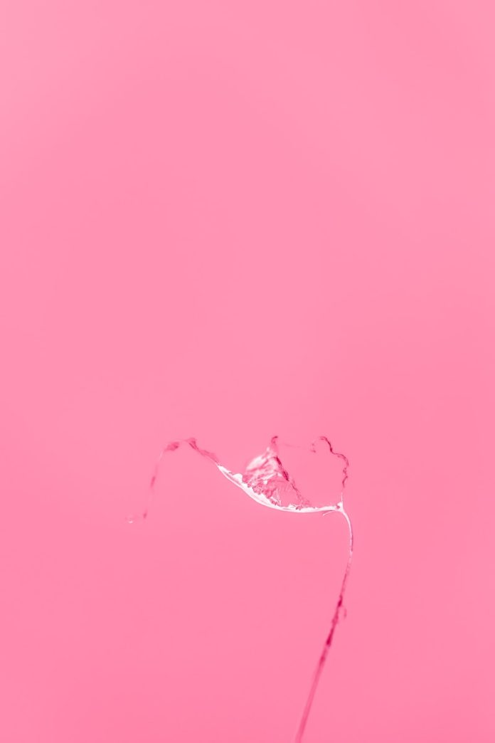 a pink background with a water drop in the middle